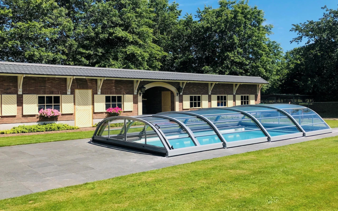 Low-profile transparent pool enclosure installed over an outdoor swimming pool