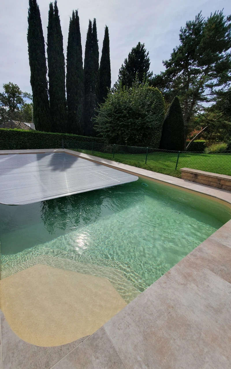 Piscine paysagée avec volet immergé et jardin arboré
